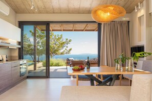 Eine moderne Küche mit Meerblick, ein Essbereich mit Tisch und Stühlen sowie ein großes Fenster mit Vorhängen.