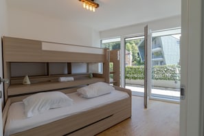 Ein modernes Schlafzimmer mit einem hölzernen Bett, eingebauten Regalen und einem großen Schiebeglasfenster, das zu einem Außenbereich führt.