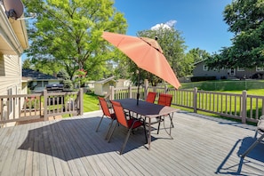 Eine Terrasse mit Tisch, Stühlen und Sonnenschirm, sowie ein Holzzaun.