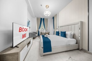 Ein modernes Hotelzimmer mit einem großen Bett, einem Schreibtisch, einem Sessel, einem Fernseher und einem Schild mit der Aufschrift 'BOOK ME'.