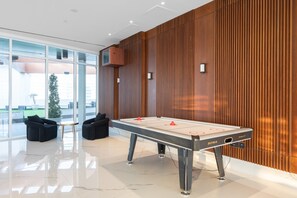 Ein Billardtisch in einem modernen Raum mit Holzvertäfelung und großen Fenstern.