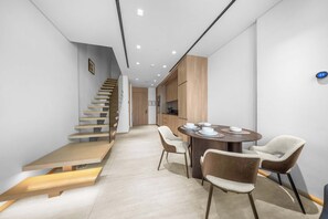 Ein modernes Interieur mit einer Treppe, einem Essbereich mit einem runden Tisch und Stühlen sowie Holzschränken.