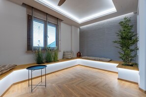 Ein modernes Interieur mit Holzboden, einer eingebauten Bank, einem Tisch und einem großen Fenster mit Jalousien.