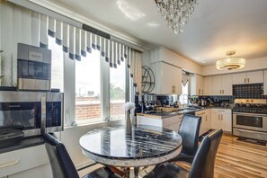 Een moderne keuken met een ingebouwde koelkast, een fornuis en een eethoek met een ronde tafel en stoelen.