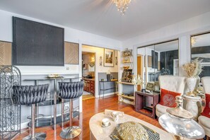Ein großzügiges Wohnzimmer mit hoher Decke, einer Bar mit Hockern und einem Essbereich mit Tisch und Stühlen.