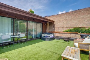Eine Terrasse mit Kunstgr Rasen, einer runden Sitzecke und einem Holztisch.