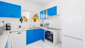 Eine moderne Küche mit weißen und blauen Schränken, einem Geschirrspüler, einer Mikrowelle und einem Kühlschrank.