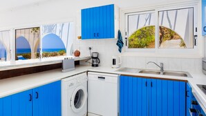 Eine moderne Küche mit blauen Schränken, einer Waschmaschine und einer Kaffeemaschine.