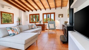 A living room with a sofa, a chair, a fireplace, and large windows. - Villa Sa Pleta in Mallorca (Son Servera)