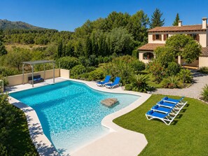 A swimming pool with lounge chairs, a pergola, and a house with a tiled roof. - Villa Sa Pleta in Mallorca (Son Servera)