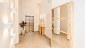 A modern hallway with a wooden-framed mirror, a wall-mounted light fixture, and a potted plant. - Ereza Residence 5 in Arrecife (Arrecife)