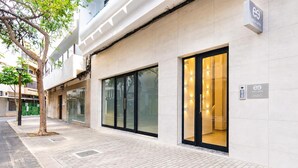 A modern building with glass doors and windows, a paved sidewalk, and a tree. - Ereza Residence 5 in Arrecife (Arrecife)