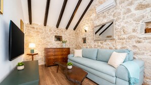 Ein Zimmer mit Steinwand, Holzschrank, hellblauem Sofa, Couchtisch aus Holz und Flachbildfernseher.
