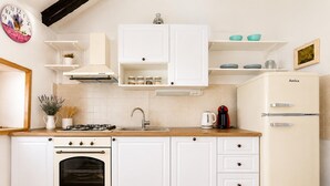 Eine Küche mit weißen Schränken, einem Herd, einem Backofen, einer Spüle und einem Kühlschrank.