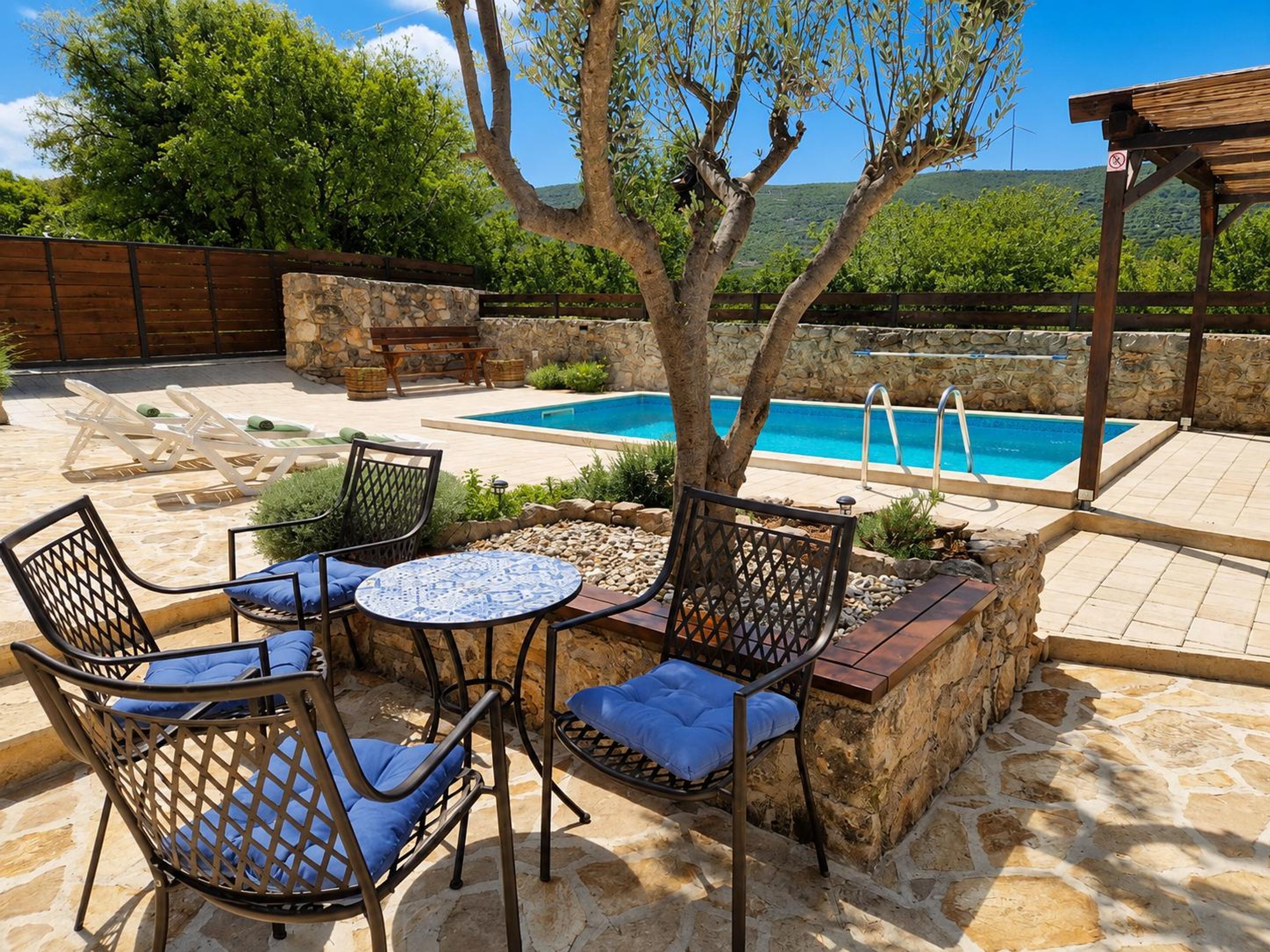 A poolside area with stone flooring, a pool, lounge chairs, and a pergola.