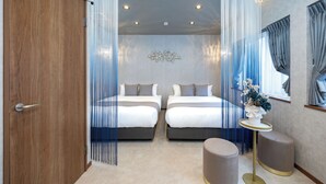 Ein Schlafzimmer mit zwei Betten, einem runden Tisch und einer Zierpflanze.