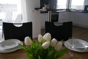 Ein Esstisch mit weißen Tellern, einem Weinglas und einem Strauß weißer Tulpen.