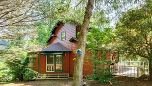 A small wooden cabin with a porch, surrounded by trees and a fenced yard. - Hiawassee Porch: Getaway Near River, Lake & Trails (Hiawassee)