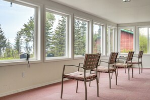 Ein Zimmer mit großen Fenstern, einem rosafarbenen Teppich und vier Stühlen mit gepolsterten Sitzen und Rückenlehnen.