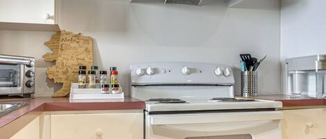 A kitchen with a white stove, a toaster, and a map of Alaska on the counter.