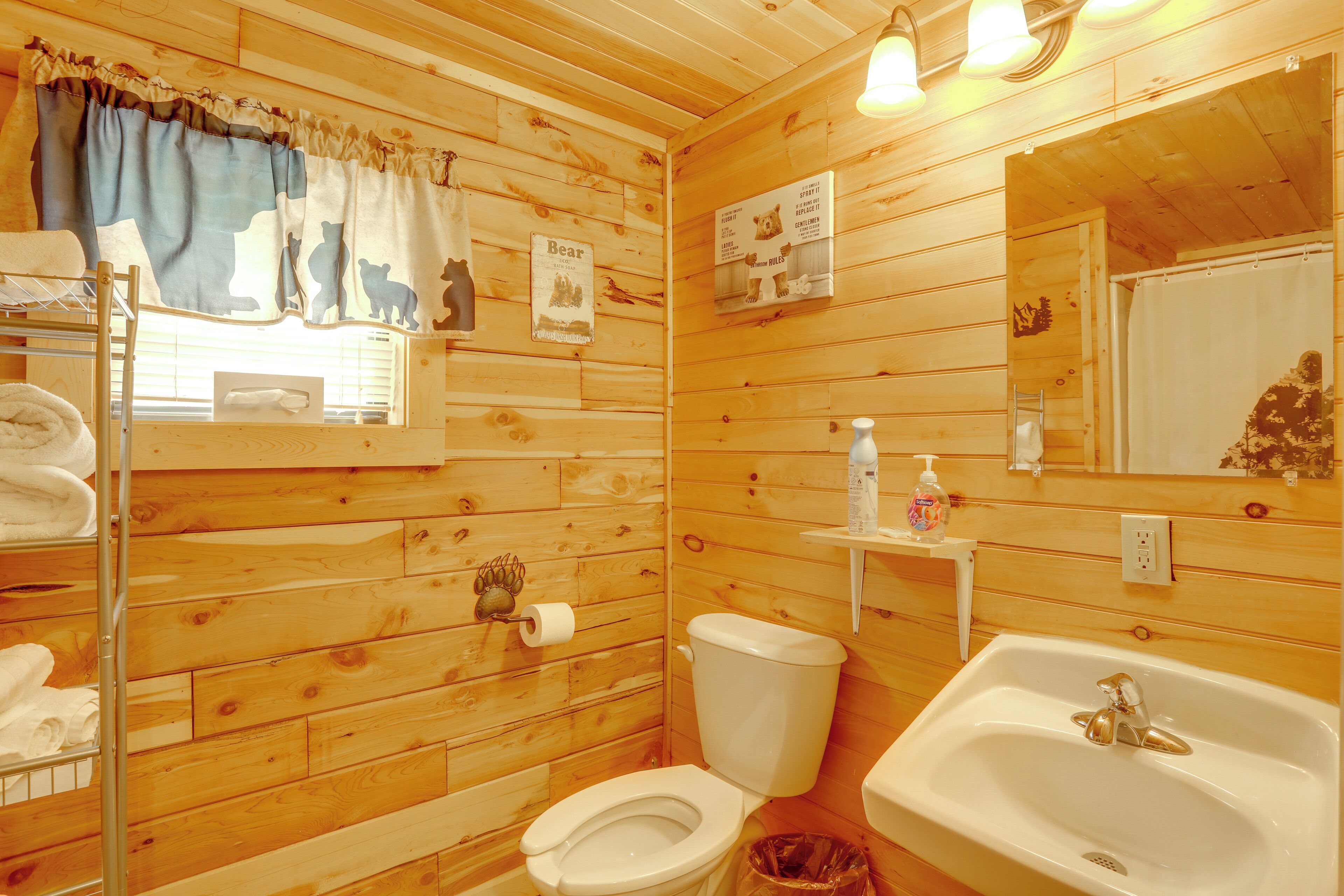 A wooden cabin bathroom with a toilet, sink, and towel rack.
