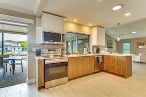 Een moderne keuken met een centraal eiland, inbouwapparatuur en een zithoek buiten.