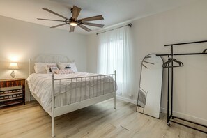 Ein Schlafzimmer mit einem Bett, einem Deckenventilator, einem Nachttisch mit Lampe und einem Kleiderschrank.
