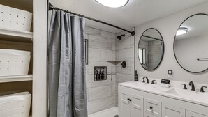 A bathroom with a bathtub, a large mirror, and a vanity with a sink. - Historic Prescott Gem! Walk to Whiskey Row! (Prescott)