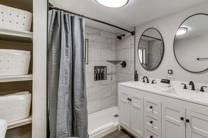 A bathroom with a bathtub, a large mirror, and a vanity with a sink. - Historic Prescott Gem! Walk to Whiskey Row! (Prescott)