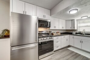 A modern kitchen with stainless steel appliances, white cabinetry, and a marble backsplash. - Historic Prescott Gem! Walk to Whiskey Row! (Prescott)