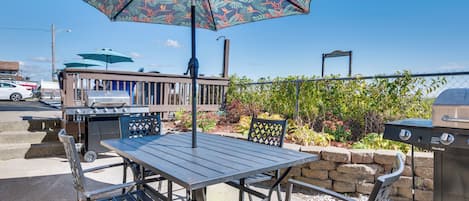 Un patio al aire libre con una mesa, sillas, una parrilla y un parasol decorativo.