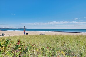 Ein Strand mit einer grasbewachsenen Vordergrund, sandigem Strand und dem Meer im Hintergrund.