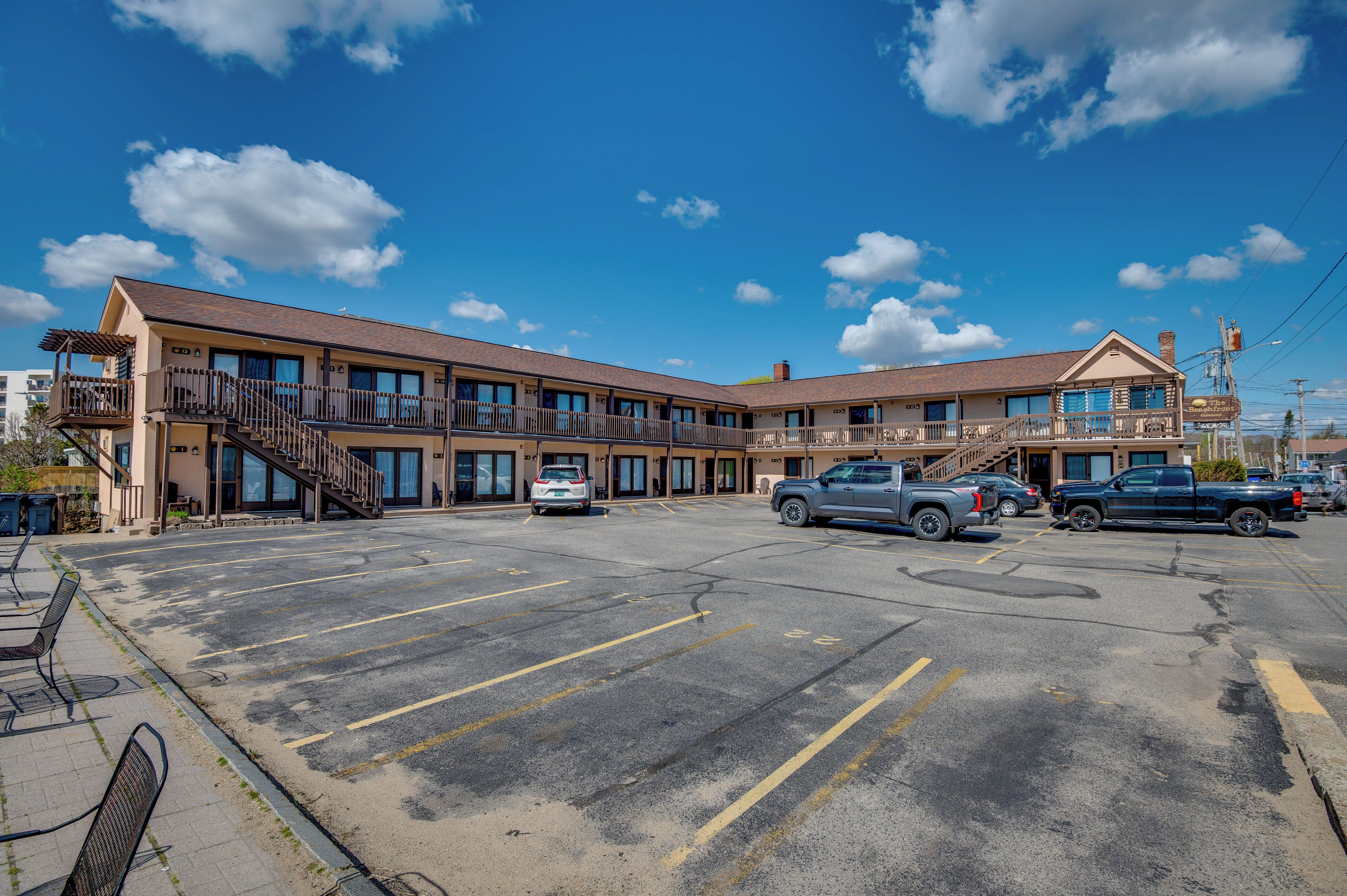 Un motel doté d’un parking, d’un espace extérieur abrité avec des sièges, et d’un bâtiment comportant de nombreuses fenêtres et des balcons.