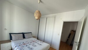 A bedroom with a bed, bedside tables, a hanging light fixture, a wardrobe, and a door leading to another room. - Downtown Baixa-Rossio Central, Lisbon, with Parking (Lisboa)