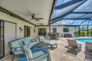 Eine überdachte Terrasse mit Pool, Gartenmöbeln und Deckenventilator.
