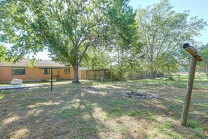 A backyard with a tree, a stone fire pit, and a house in the background. - Suburban Sanctuary: Magnolia Home w/ Backyard! (Magnolia)