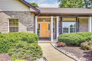A two-story house with a front porch, a wooden door, and a brick exterior. - Gateway to St Louis: Group Getaway w/ Game Room (Florissant)