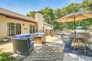 A patio with wicker furniture, a table with chairs, and umbrellas.