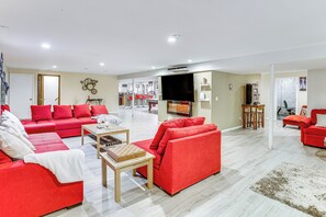 Ein geräumiges Wohnzimmer mit roten Sofas, einem Flachbildfernseher und einem Essbereich mit Tisch und Stühlen.