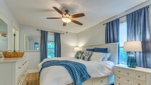 A bedroom with a bed, a dresser, a nightstand, a ceiling fan, and a window with curtains. - Downtown Gem: Walk to Restaurants & Palafox St! (Pensacola)