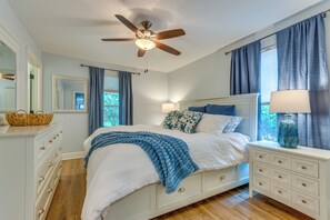 A bedroom with a bed, a dresser, a nightstand, a ceiling fan, and a window with curtains. - Downtown Gem: Walk to Restaurants & Palafox St! (Pensacola)
