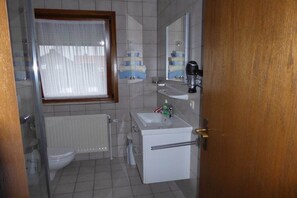 Kylpyhuone, jossa on wc, pesuallas, peili ja ikkuna.