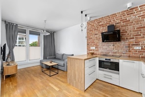 A compact kitchen with a modern design, a built-in oven, and a dining area with a small table and a sofa. - Riverside Residence • 1BR • Elevator • Old Town (Kraków)