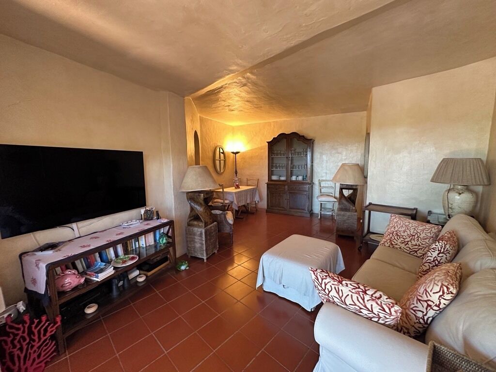Una sala de estar con un sofá, televisión, aparador y una mesa con lámpara.
