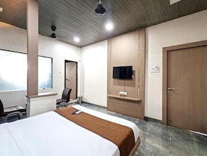 A hotel room with a bed, a desk, a chair, a television, and a wardrobe. - Hotel Royal Inn (Panvel)