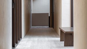 Un pasillo con un banco, suelo de madera y ventanas amplias que dejan entrar luz natural.