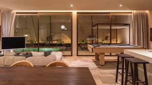 Una sala de estar moderna con mesa de billar, televisor de pantalla plana y sofá.