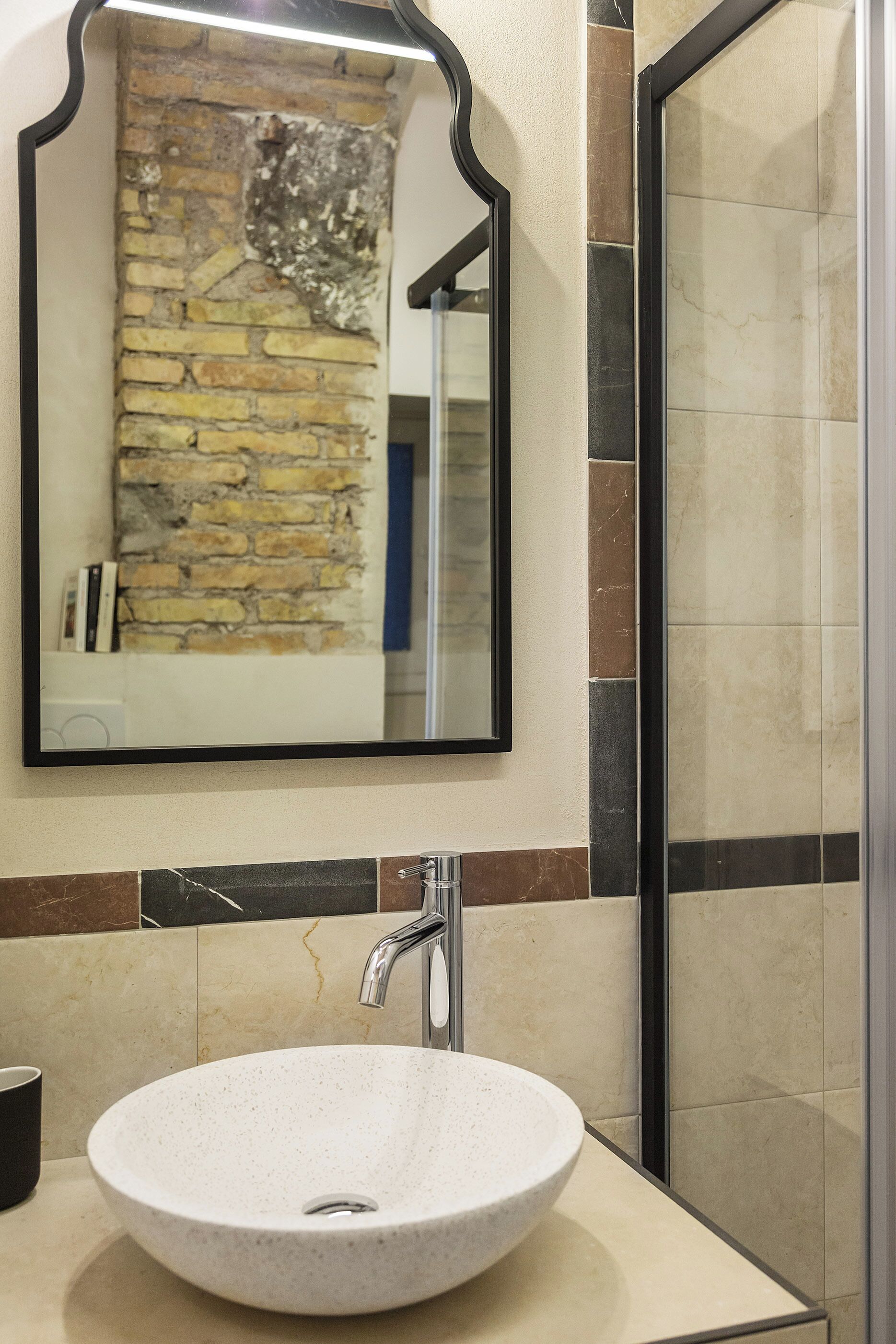 Un baño con un lavabo redondo, un espejo y una zona de ducha.
