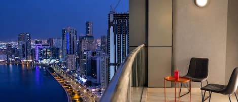 A balcony with a view of a city skyline at dusk, featuring modern buildings and a waterfront.