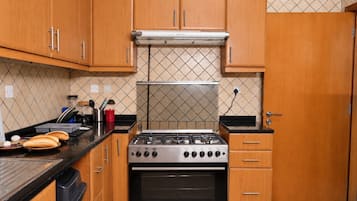 A kitchen with wooden cabinets, a gas stove, and a tiled backsplash.
